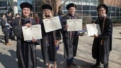 graduates holding their diplomas