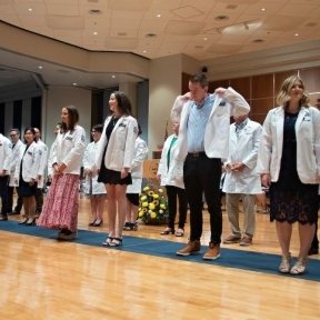 student on stage wearing white coat
