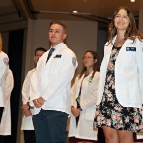 student on stage wearing white coat