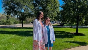 Participating students in their white coats gather for an environmental photo.