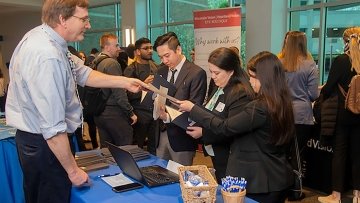 Midwestern Employee passing out brochures at career fair to prospective students.