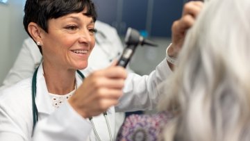 Doctor demonstrating how to check an ear 