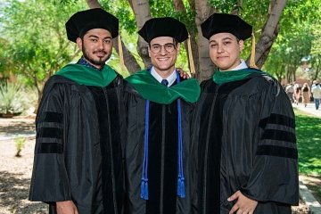 Three graduates standing in front of a tree for a group photo