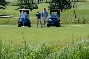 Attendees play golf and drive the golf carts