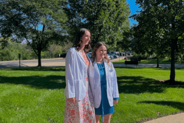 Participating students in their white coats gather for an environmental photo.