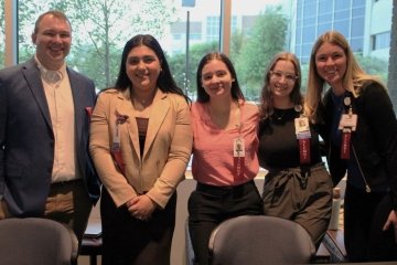 Alumni students pose for a photo in a line with their red alumni ribbons at the CAREERxPO. 