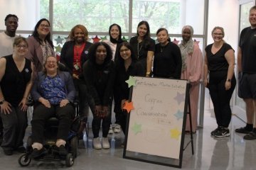 Gathering of students and University staff by the coffee and conversation poster.