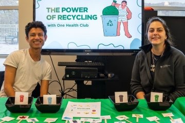 Members of the One Health Club display information about proper recycling methods with a PowerPoint presentation, photos of items, and small bins for attendees to guess where the items should be recycled. 