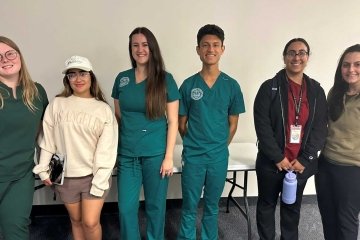 Members of the One Health Club gather for a photo in a line.