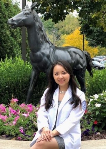 Chong Lee in white coat in front of a horse statue.