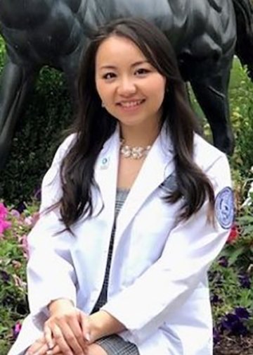 Chong Lee in white coat in front of a horse statue.