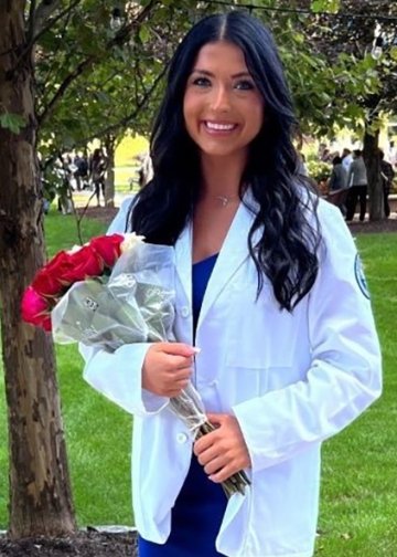 Martina Golaszewski in a white coat photo holding red roses.