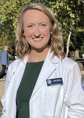 Student posing on campus in white coat