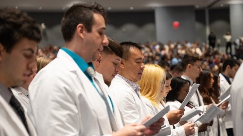 CCOM and CPDG first year students recite their commitment while wearing white coats.