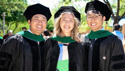 Three osteopathic medicine graduates wear graduation gowns.