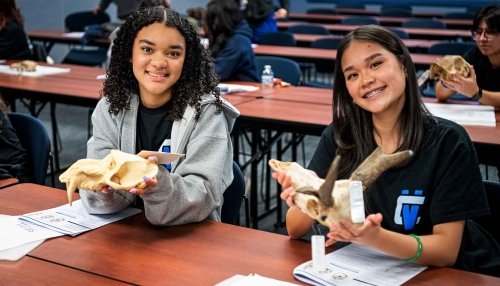 Two high school students holding up bones