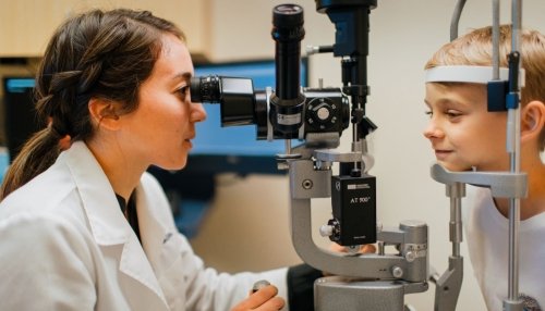 Optometrist examines young boy's eye.