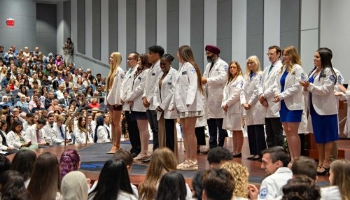 student on stage for white coat ceremony