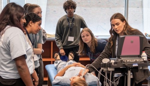 High school students practice using imaging machine.