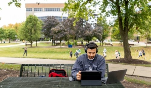 Student on laptop studying outside.