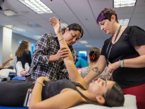 Professor and student working on patient’s arm.