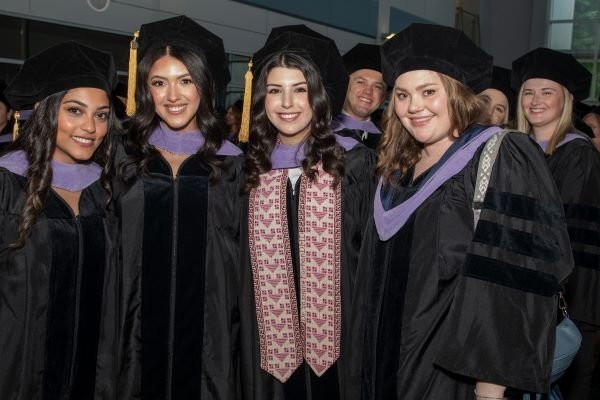 Graduating dental students pose for a photo in caps and gowns.