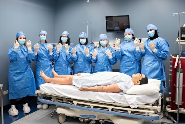 High school students washed their hands and donned scrubs, gowns, and gloves to practice preparing for surgery. They also had an interactive session with a mannikin patient. 