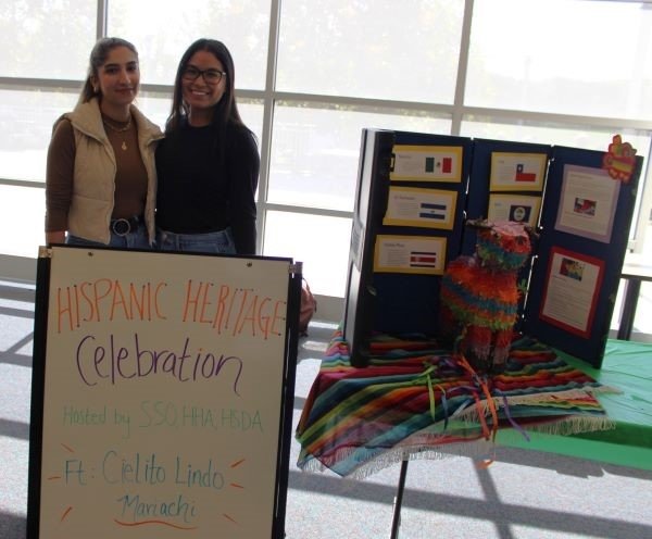 Students gather by the Hispanic Heritage Month informational poster. 