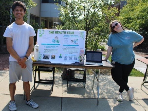 Students stand before the poster about the One Health Club.