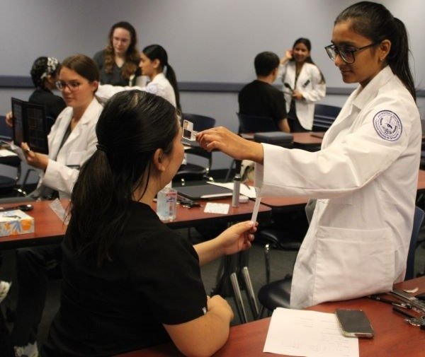 Optometry students perform vision tests on dental students. 